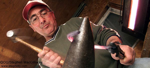 Farrier Paul Jennings hammers a white
 hot horse shoe into shape